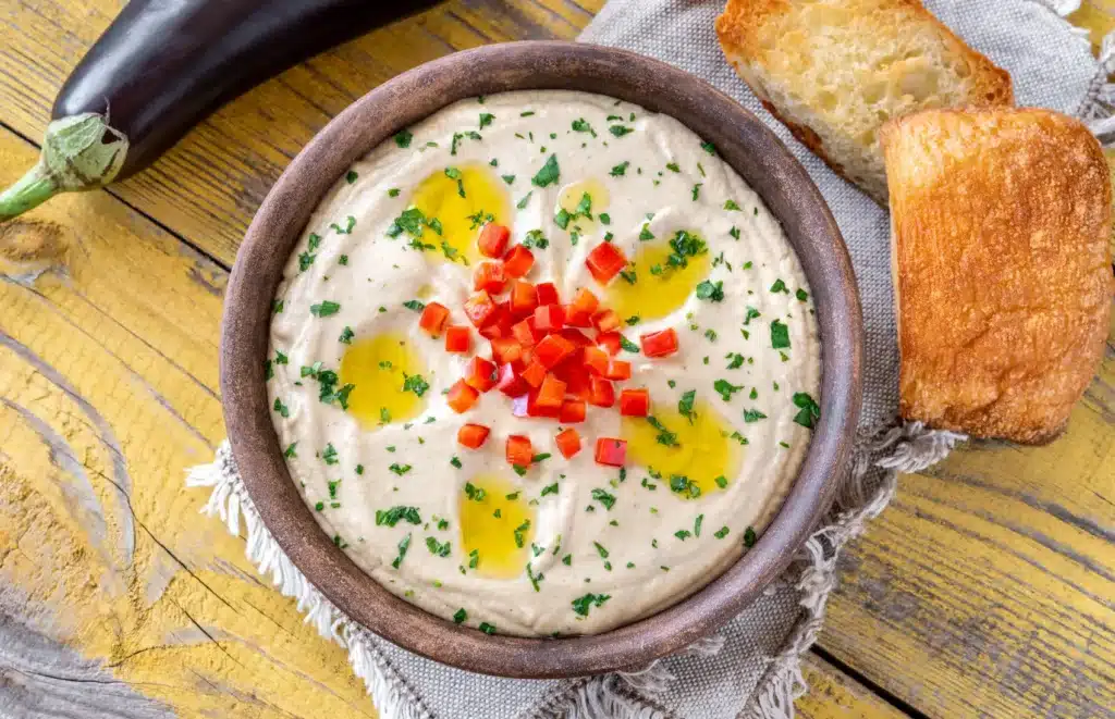 Bol de Moutabal libanais crémeux, décoré d’un filet d’huile d’olive et de persil, prêt à être dégusté comme mezzé.