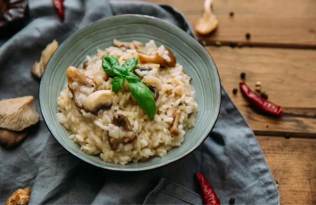 Risotto italien crémeux aux champignons, servi dans une assiette blanche avec parmesan et persil