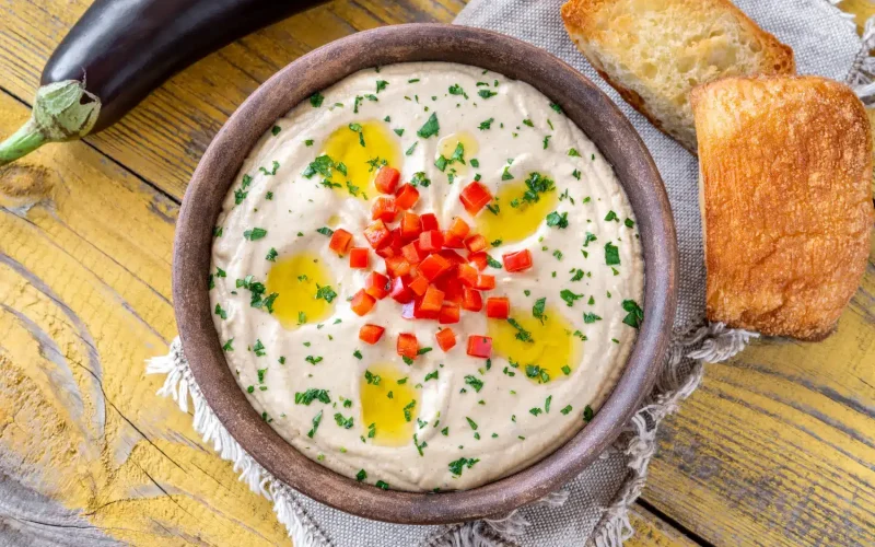 Bol de Moutabal libanais crémeux, décoré d’un filet d’huile d’olive et de persil, prêt à être dégusté comme mezzé.