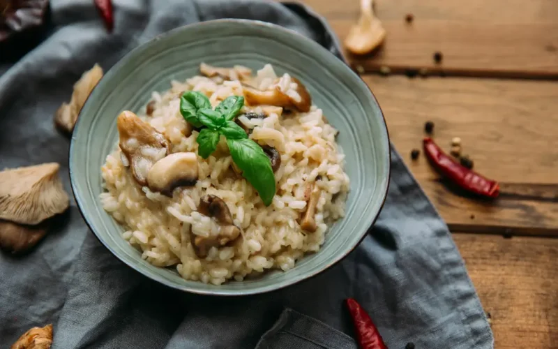 Risotto italien crémeux aux champignons, servi dans une assiette blanche avec parmesan et persil